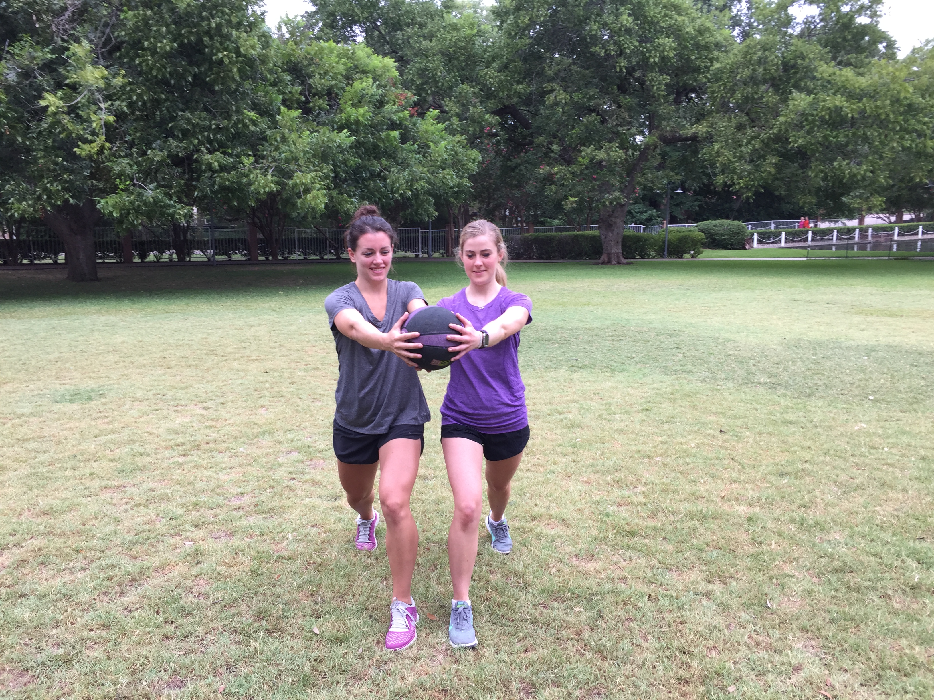Two women doing a lunge stance/rotational ball pass