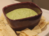 Bowl of green salsa surrounded by tortilla chips and tomatillos